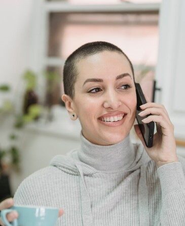 happy woman with short hair on phone with coffee